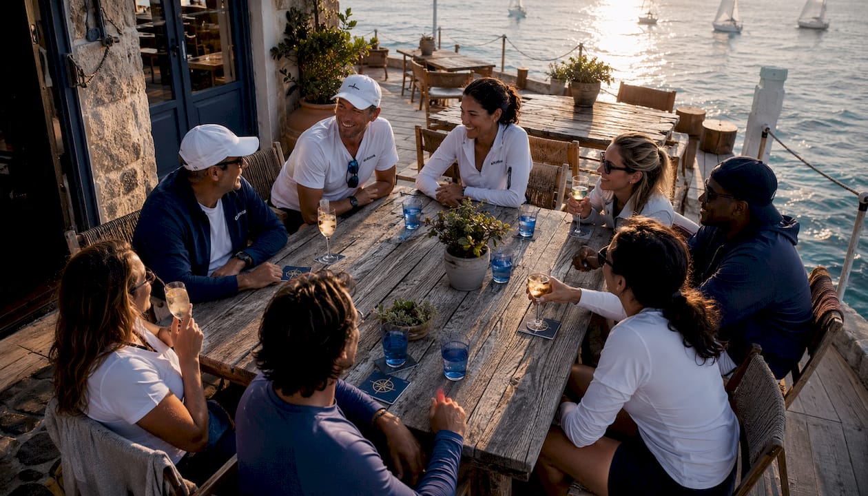 Solo travelers socializing on sailboat deck at sunset
