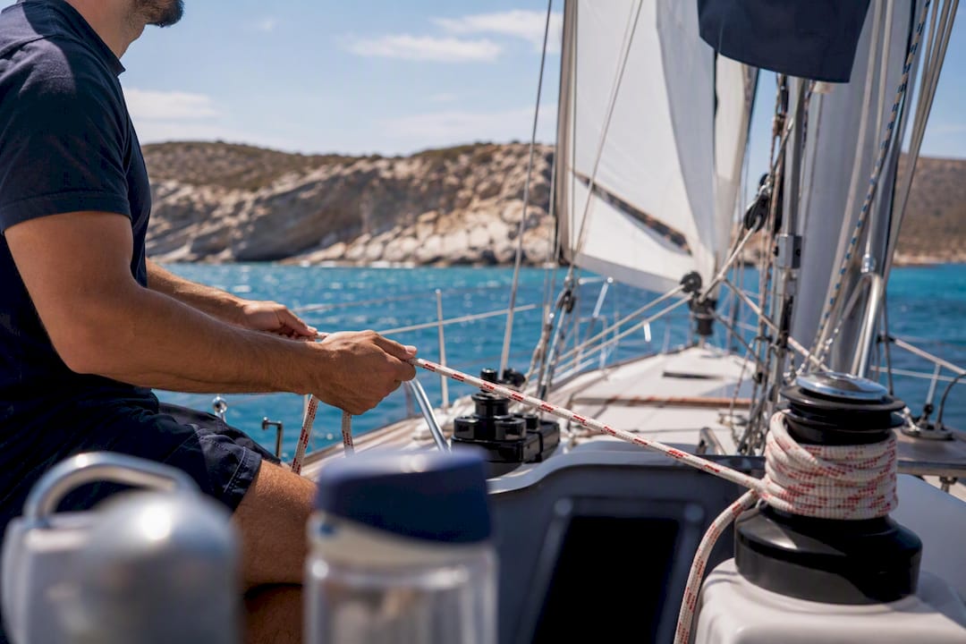 Skipper adjusting sail ropes on yacht near Cyclades coast