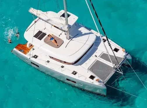 Catamaran alb ancorat în apă turcoaz, fotografiat de sus