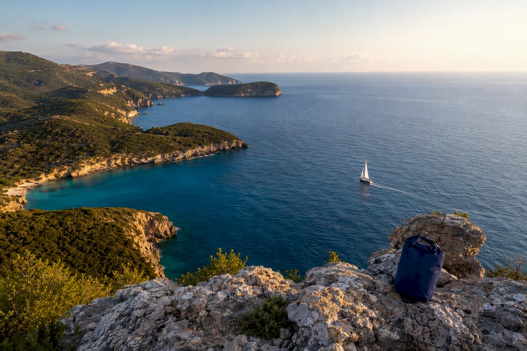 Sailboat rounding an Ionian island headland