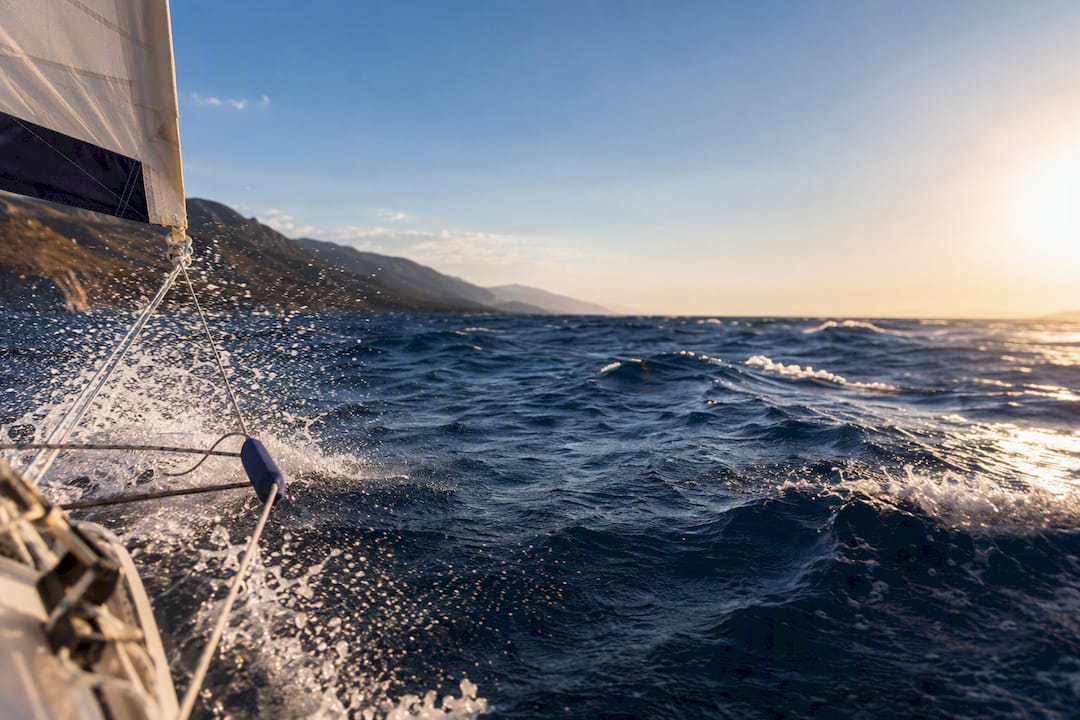 Sailors handling a reefed sail in rough Aegean water