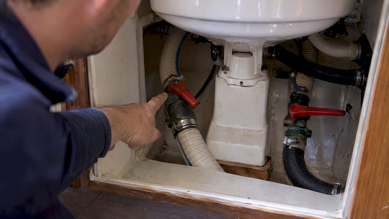Seacock handles and hoses beneath a marine toilet